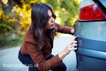 photo of lady looking at a scratch on her car